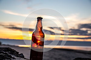 Beer bottle reflected on the beach at sunset