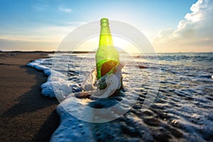 Beer bottle on a sandy beach with clear sky