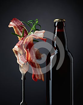 Beer bottle and slices of fried bacon