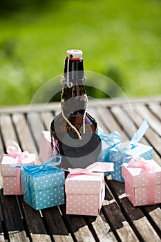 Beer bottle with small gifts on garden table, father`s day,