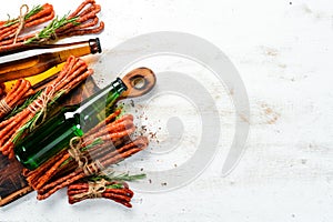 Beer in bottle and smoked sausage on white wooden background. Beer, Kabanosy. Top view.