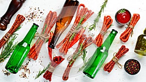 Beer in bottle and smoked sausage on white wooden background. Beer, Kabanosy. Top view.