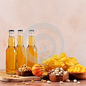 Beer in bottle and snack on wooden table with basketball ball, game night food