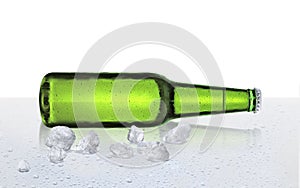 Beer bottle with water drops and ice cubes on white background