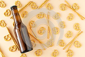 Beer bottle and yellow background of pretzels on yellow background. Copy space