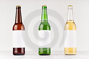 Beer bottles 500ml different colors with blank white label on white wooden board, mock up.