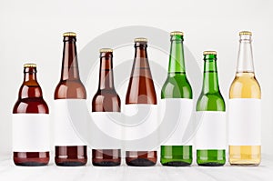 Beer bottles collection different type and colors with blank white label on white wooden board, mock up.