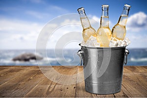 Beer bottles in ice on beach background