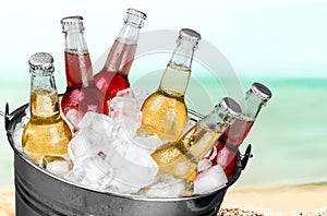 Beer bottles in ice on beach background