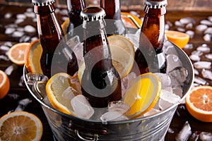 beer bottles in a metal bucket with ice, sprinkled with citrus slices