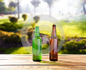 Beer bottles on wooden table on park blurred background, alcoholic drinks celebration