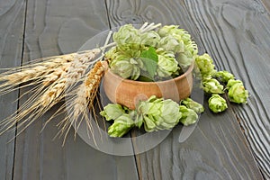 Beer brewing ingredients Hop cones in wooden bowl and wheat ears on dark wooden background. Beer brewery concept. Beer background