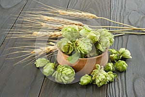 Beer brewing ingredients Hop cones in wooden bowl and wheat ears on dark wooden background. Beer brewery concept. Beer background