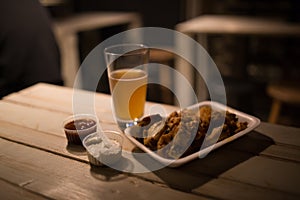 Beer, chicken wings and sauce on the table in pub