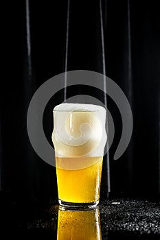 Beer. Cold Craft light Beer in a glass with water drops. Pint of Beer into a tall glass with a thick foam