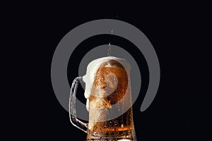 Beer. Cold Craft light Beer in a glass with water drops on the wooden table over the black background