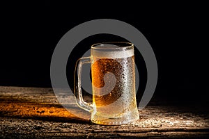 Beer. Cold Craft light Beer in a glass with water drops on the wooden table over the black background