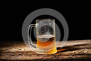 Beer. Cold Craft light Beer in a glass with water drops on the wooden table over the black background