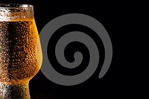 Beer. Cold Craft light Beer in a glass with water drops on the wooden table over the black background