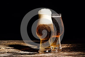 Beer. Cold Craft light Beer in a glass with water drops on the wooden table over the black background