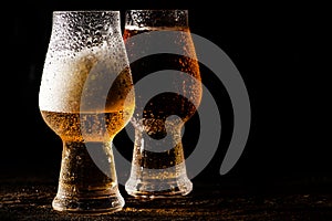 Beer. Cold Craft light Beer in a glass with water drops on the wooden table over the black background