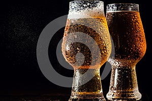 Beer. Cold Craft light Beer in a glass with water drops on the wooden table over the black background