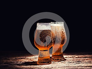 Beer. Cold Craft light Beer in a glass with water drops on the wooden table over the black background