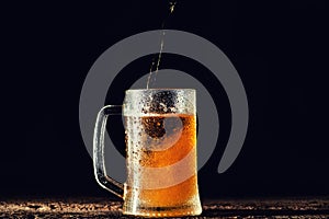 Beer. Cold Craft light Beer in a glass with water drops on the wooden table over the black background