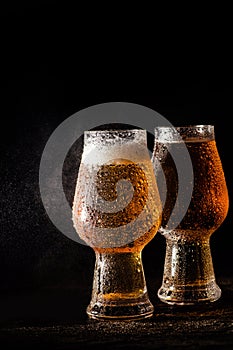 Beer. Cold Craft light Beer in a glass with water drops on the wooden table over the black background