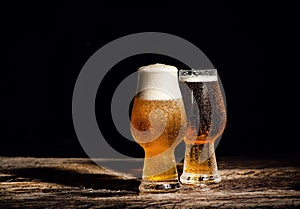 Beer. Cold Craft light Beer in a glass with water drops on the wooden table over the black background