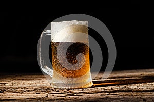 Beer. Cold Craft light Beer in a glass with water drops on the wooden table over the black background