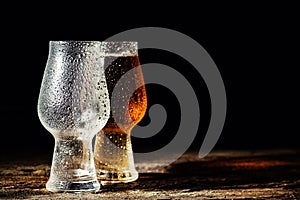 Beer. Cold Craft light Beer in a glass with water drops on the wooden table over the black background