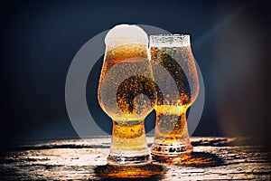 Beer. Cold Craft light Beer in a glass with water drops on the wooden table over the black background