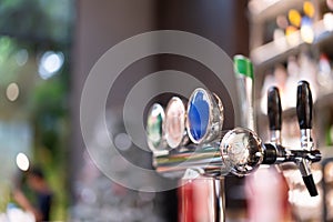 Beer dispenser sits on shelf in front of vintage bar, bokeh light background. Alcoholic drinks in pubs for weekend parties