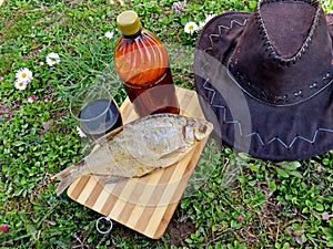 Beer and dried fish on a bamboo board on a lawn