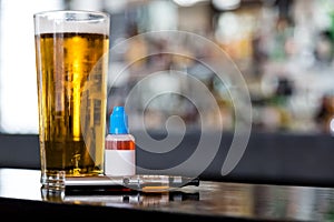 Beer, e-liquid and vaporizer on the bar