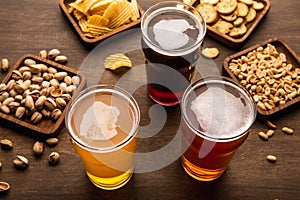 Beer festival in the pub. Various of beer, crackers, peanuts, pistachios and chips in plates and sprinkled on table