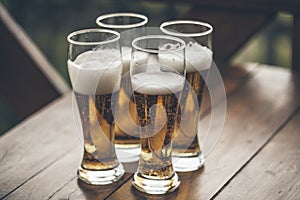 Beer with foam light tall boys standing on a wooden table closeup