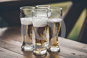 Beer with foam light tall boys standing on a wooden table closeup