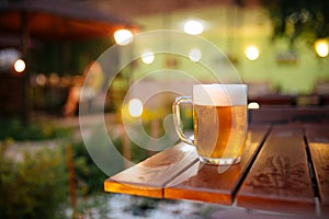 Beer with foam outside blurry lights background