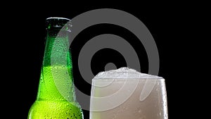 Beer Froth Pouring into a Glass. Cold lager beer. Green beer bottle.