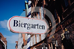 Beer garden sign. Opened shield in german biergarten on a sunny holiday. Old traditional german buildung in background photo