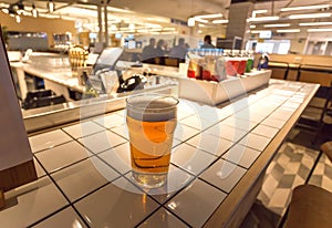Beer in glass of bar in airport lounge, and people waiting for the flight