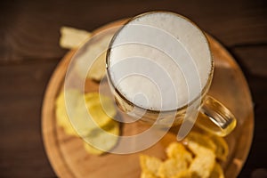 Beer glass with beer and hot smoked fish close-up. Beer mug with beer and potato chips, crackers on a dark background and copy spa