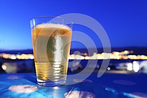 Beer glass chilled at sunset overlooking city ligh