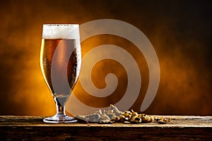 Beer glass with dark cold beer with bubble froth and peanuts on