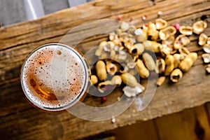 Beer glass with dark cold beer with bubble froth and peanuts on