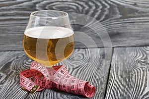 Beer in a glass and a measuring tape. On pine boards. A day without diets