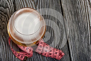 Beer in a glass and a measuring tape. On pine boards. A day without diets