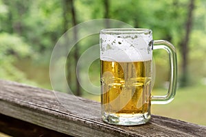 Beer in glass mug outdoors with nature background